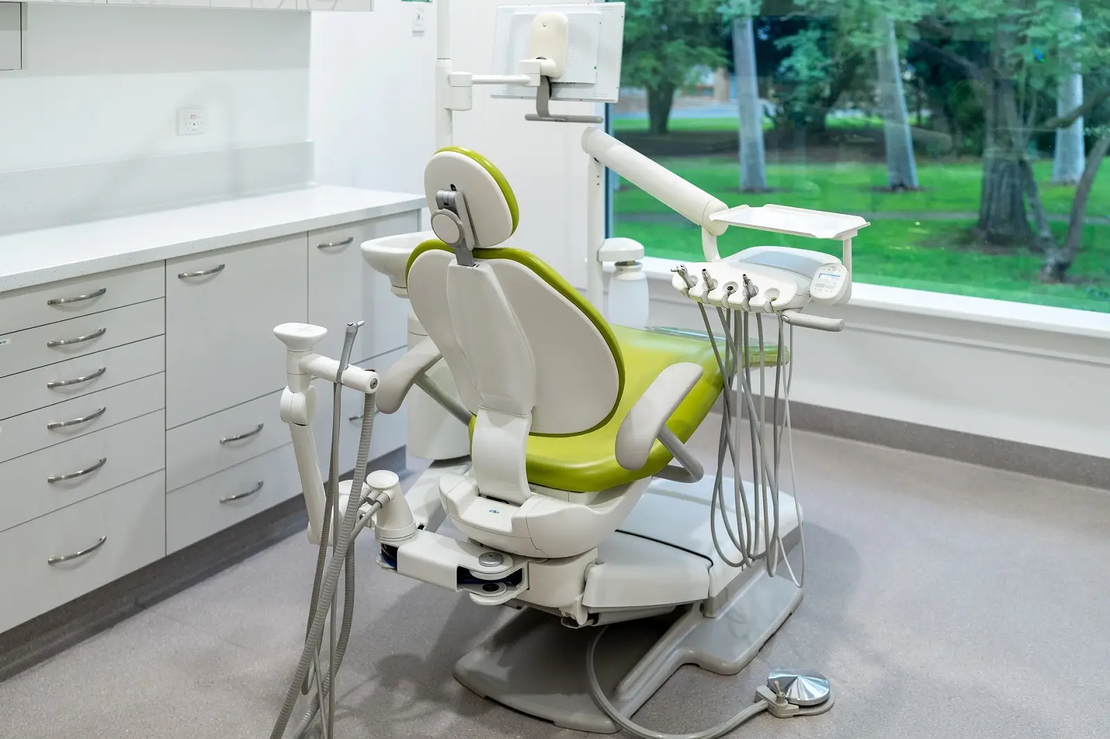 Treatment room at Fullarton Park Dental with a green dental chair and a window onto the park